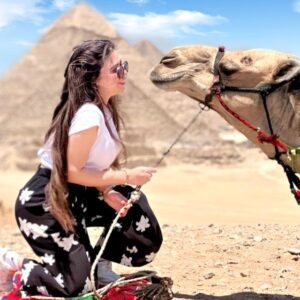 a woman kneeling next to a camel in Giza Pyramids